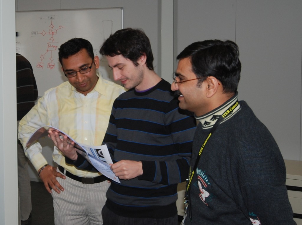 Charad Dhavel (left), Frederic Carayon (middle), and Patel Vijay (right) peruse a preliminary handbook for the new database system.